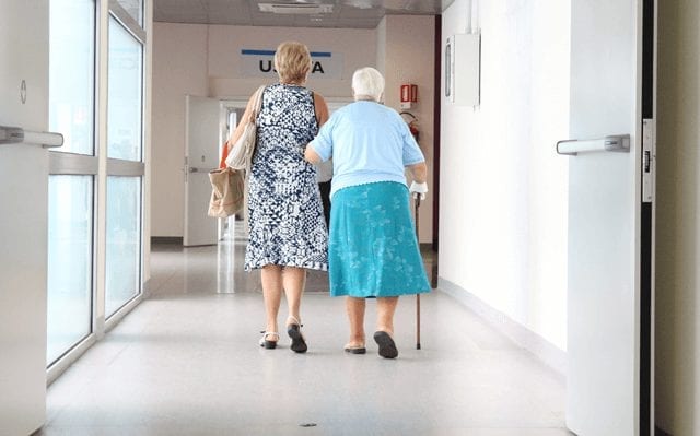 Fire doors help open with people walking through hospital corridor